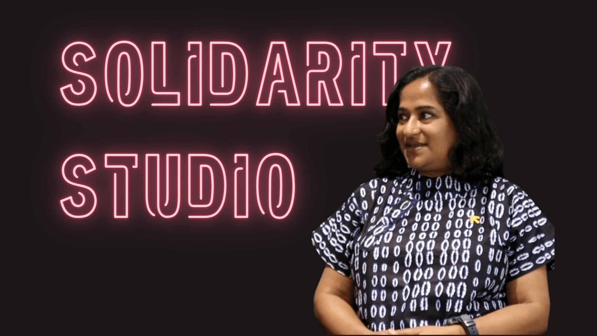 Neon pink Text with the words Solidarity Studio on a black backround and Deepti Mathew in a blue and white batik blouse.