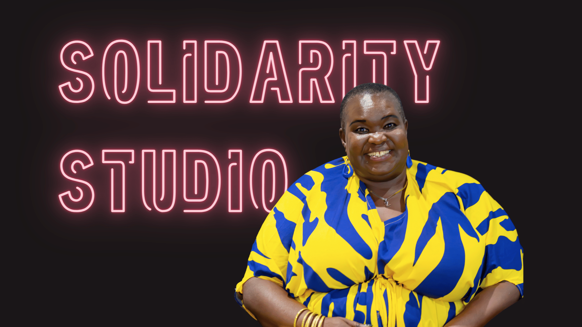 Lucy Mulombi smiling and wearing a yellow and blue dress, the background is black with a pink neon text with the words Solidarity Studio.